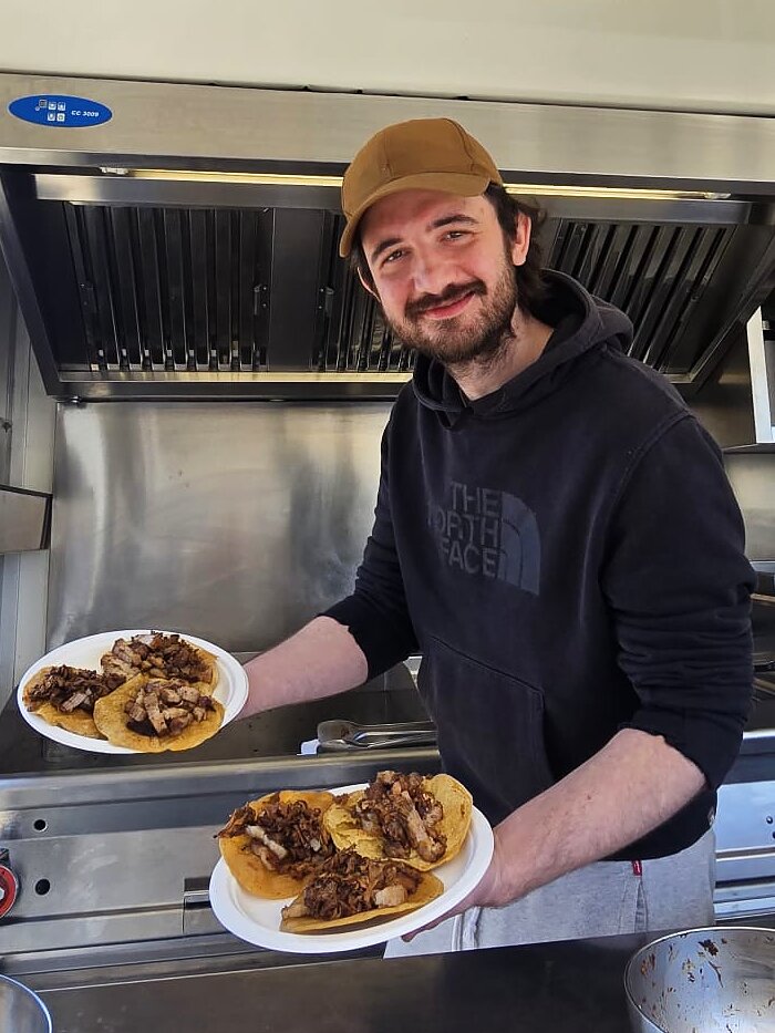 Marcello Davanzo nel food truck, con due piatti di tacos appena preparati